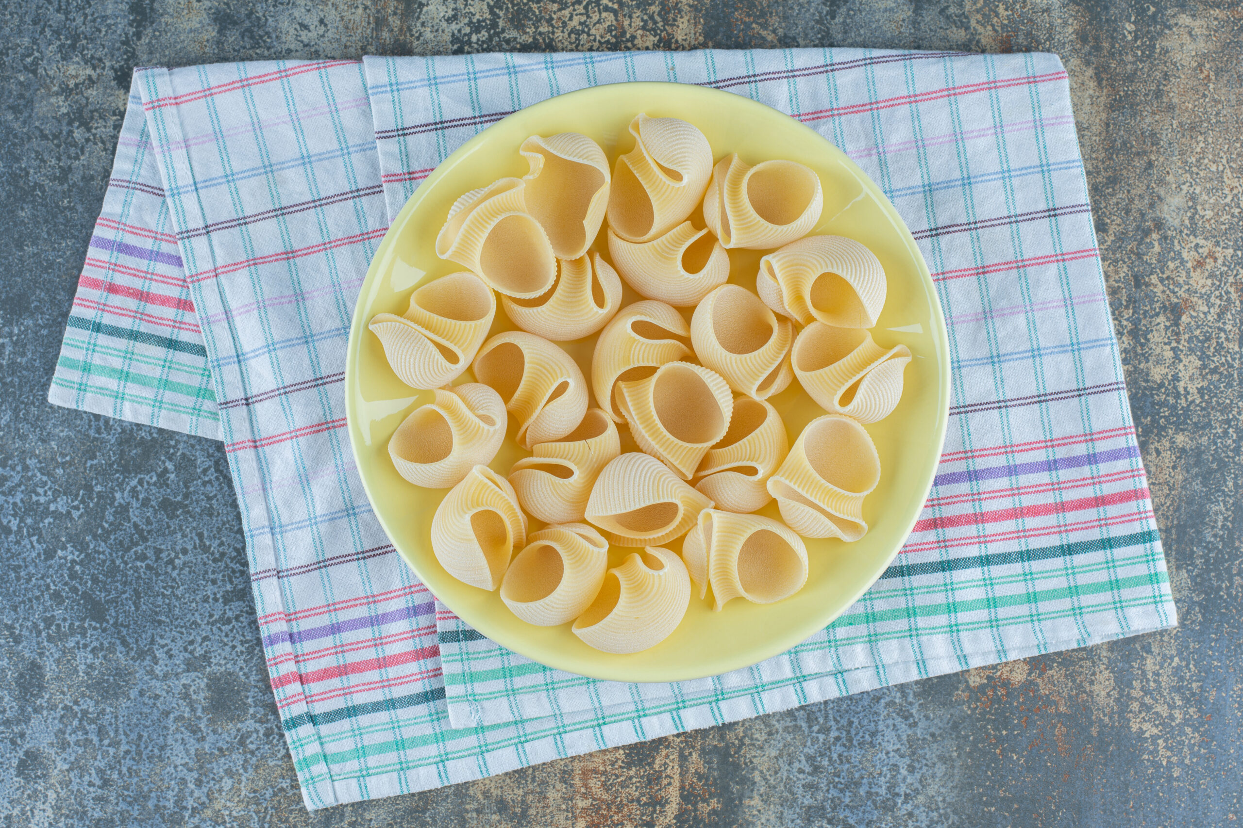 pipe rigate pasta in the bowl, on the towel on the marble background
